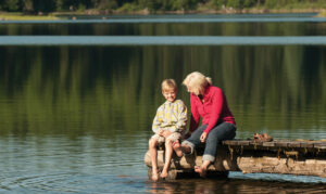 A child and woman sit on the dock on Lower Stillwater Lake - photo by Travel Montana